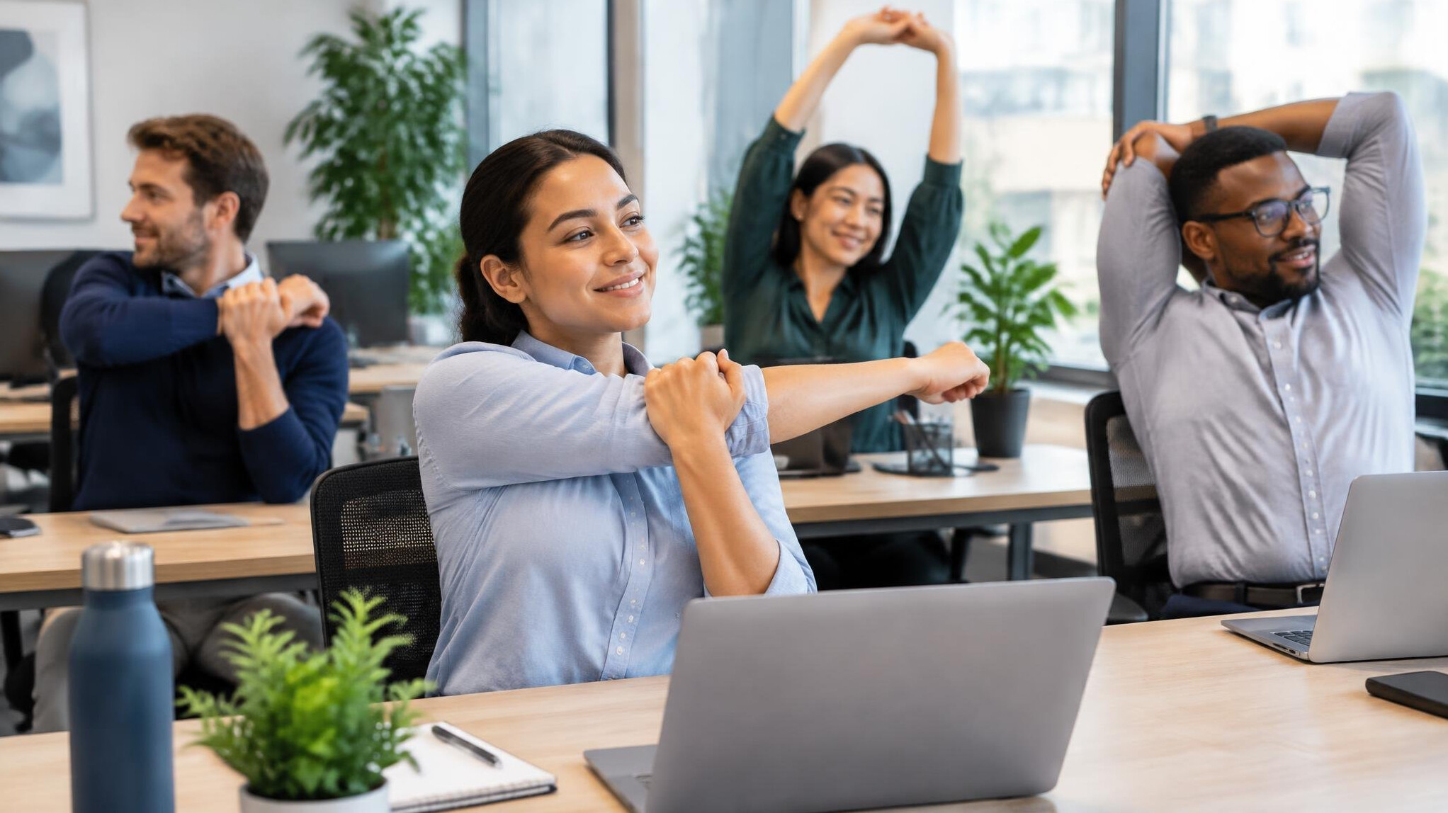 employees stretching at office desk